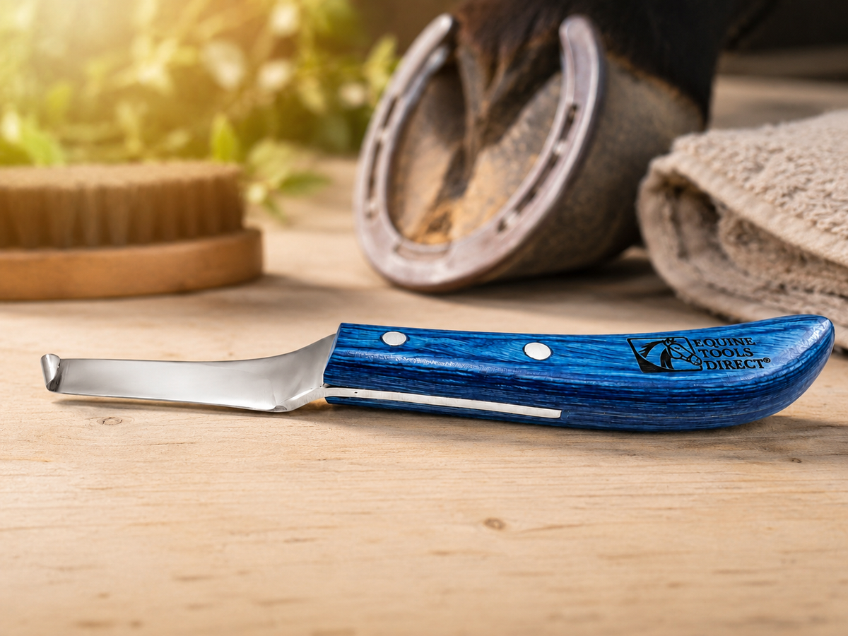 Equine Tools Direct right-hand curved hoof knife with blue handle resting on wooden fence post at horse stable